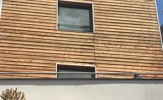 Photo de l'entretien de la façade d'une maison en bois.